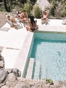 a group of people sitting around a swimming pool at Casa Om in Dosríus