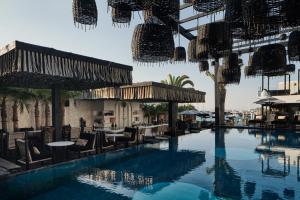 a swimming pool with tables and chairs next to a building at Myconian O, a Member of Design Hotels in Ornos