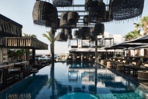 uma piscina com cadeiras e guarda-sóis em Myconian O, a Member of Design Hotels em Ornos