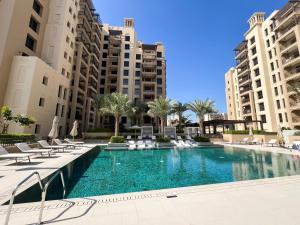 Cozy 1BR Retreat, Asayel 3 Madinat Jumeirah Living - 81AB0 في دبي: مسبح مع كراسي الصالة والمباني