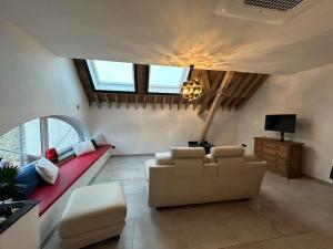 a living room with a couch and a tv at Gîte de la vieille grange in Lobbes