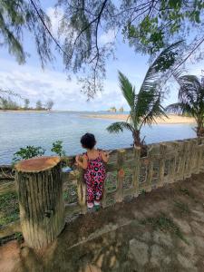 a girl standing on a fence looking at the water at Umar's Tiny House in Kemaman