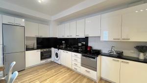 a kitchen with white cabinets and a washer and dryer at Pentelis Cozy 58sqm apt in Paleo Faliro in Athens