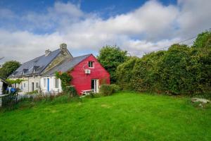 una casa rossa e bianca su un campo verde di Gîte au Calme tout équipé a Cléguérec