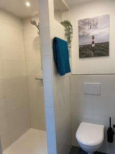 baño con ducha, aseo y una foto en Fewo Haus Peters "De Lütte", en Marschkamp