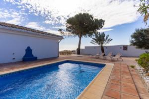 ein Swimmingpool in einem Hof mit Stühlen und einem Haus in der Unterkunft 2421 Villa Joya de Guadalupe in Manilva