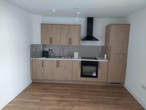 a kitchen with wooden cabinets and a sink at Guest Apartments in Redditch