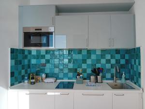 una cocina con armarios blancos y azulejos azules en la pared en Raggio di Luna, en Manarola