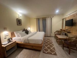 a bedroom with a large bed and a desk and a chair at HighField Villa in Kanatal