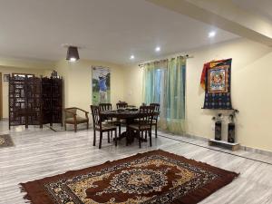 a dining room with a table and chairs and a rug at HighField Villa in Kanatal