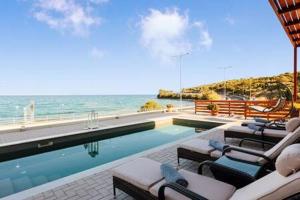 una piscina con tumbonas y el océano en Seaside Summer Bliss - Aurora Luxury Pool Paradise, en Petalidi