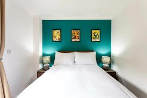 a bedroom with a white bed and a green wall at Light and airy upside down house in Boho Hackney in London