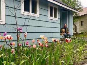 mężczyzna i pies siedzący w drzwiach domu w obiekcie Two Lakes Guesthouse w mieście Seward