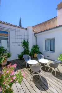 une terrasse en bois avec des tables et des chaises. dans l'établissement Hotel Le Clocher, à Ars-en-Ré