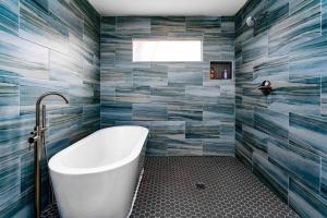 baño con bañera blanca y azulejos azules en East Atlanta / Decatur retreat with fire-pit en Decatur