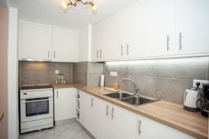 a kitchen with white cabinets and a sink at Lardigo Apartments in Argostoli