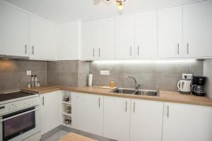 a white kitchen with white cabinets and a sink at Lardigo Apartments in Argostoli