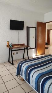 um quarto com uma cama e uma mesa com uma televisão na parede em Habitación privada en casa de huespedes em Guadalajara