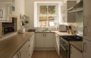 a kitchen with white cabinets and a sink and a window at Stationmasters Lodge in Stromeferry