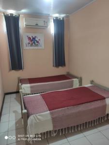 two beds in a room with blue curtains at Pousada San Salvador in Salvador