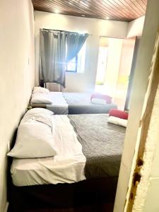 2 Betten in einem Zimmer mit 2 Fenstern in der Unterkunft Pousada Praia do Recreio in Rio de Janeiro