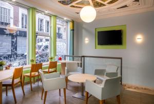 um restaurante com mesas e cadeiras e uma televisão em Saint Georges Lafayette em Paris