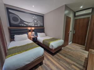 um quarto de hotel com duas camas e um quadro na parede em London Court Hotel em Londres