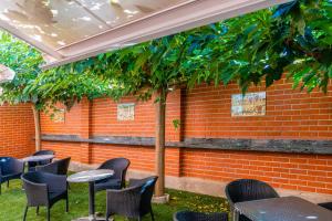 eine Terrasse mit Tischen und Stühlen vor einer Ziegelwand in der Unterkunft Hotel Palacios in Alfaro