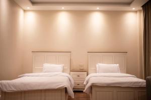 two beds with white blankets and pillows in a room at Munir’s residence in Cairo