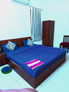 a bedroom with a bed with blue sheets and a chair at Hotel S-14 in Jaipur