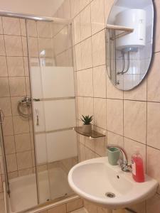 uma casa de banho com um lavatório e um chuveiro com um espelho. em sunny apartments near the sandy beach em Omiš