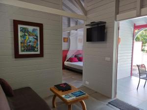 a living room with a tv and a room with a bed at Caraïbes Cottage Grenat piscine privée 900m de Grande anse in Deshaies
