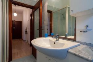 La salle de bains est pourvue d'un lavabo blanc et d'un miroir. dans l'établissement Appartamento AZ, à Follonica