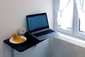 un ordenador portátil sentado en una mesa junto a un plato de pan en L’Impérial - HyperCentre - WIFI, en Étampes