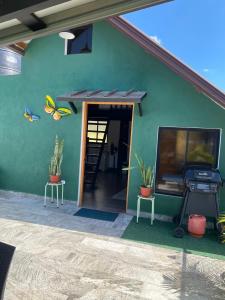 un edificio verde con una parrilla y plantas. en Lovely tiny studio, en Jarabacoa