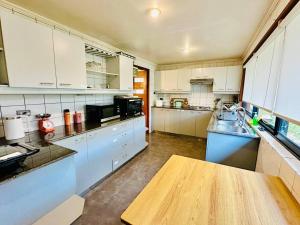 cocina grande con armarios blancos y mesa de madera en Casa con vista a playa y laguna, en Dichato