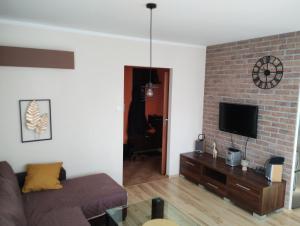 a living room with a couch and a brick wall at Green Apartment z bezpłatnym parkingiem in Olsztyn