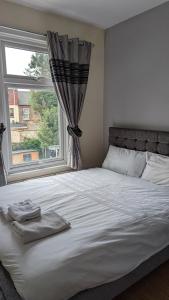1 dormitorio con 1 cama blanca grande y ventana en 3 bedroom house,4beds, 2 baths Ilford ,12 mins to Stratford, en Londres