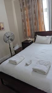 1 dormitorio con 1 cama con 2 toallas en 3 bedroom house,4beds, 2 baths Ilford ,12 mins to Stratford en Londres