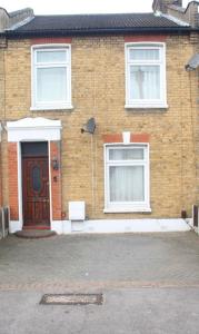 una casa de ladrillo con una puerta marrón y dos ventanas en 3 bedroom house,4beds, 2 baths Ilford ,12 mins to Stratford, en Londres