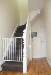a staircase with white railings in a house at 3 bedroom house,4beds, 2 baths Ilford ,12 mins to Stratford in London