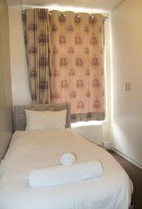1 dormitorio con 1 cama blanca y ventana en 3 bedroom house,4beds, 2 baths Ilford ,12 mins to Stratford, en Londres