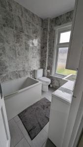 a bathroom with a tub and a toilet and a window at 3 bedroom house,4beds, 2 baths Ilford ,12 mins to Stratford in London