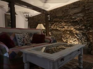 sala de estar con sofá y pared de piedra en Patones de Arriba en Patones