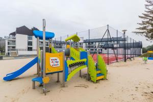 a playground with colorful equipment in the sand at Flatbook Apartamenty - Jantar Resort in Jantar