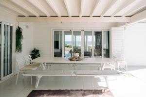 a white dining room with a table and chairs at White Sands Beach Villa in Yzerfontein
