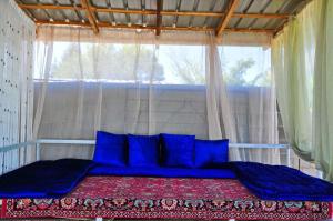 a bed with blue pillows in a room with a window at Apple Hostel Cholpon Ata in Cholpon-Ata