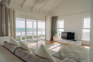 a living room with a couch and a television at White Sands Beach Villa in Yzerfontein
