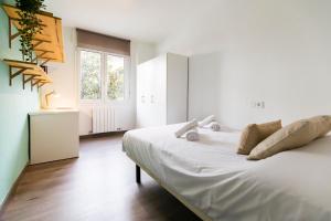 a bedroom with a white bed and a window at AkomodaT en apartamento luminoso junto al paseo de la ría in Bilbao