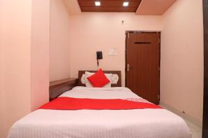 Un dormitorio con una cama con una almohada roja. en Flagship Hotel Royal Paradise en Tīrath